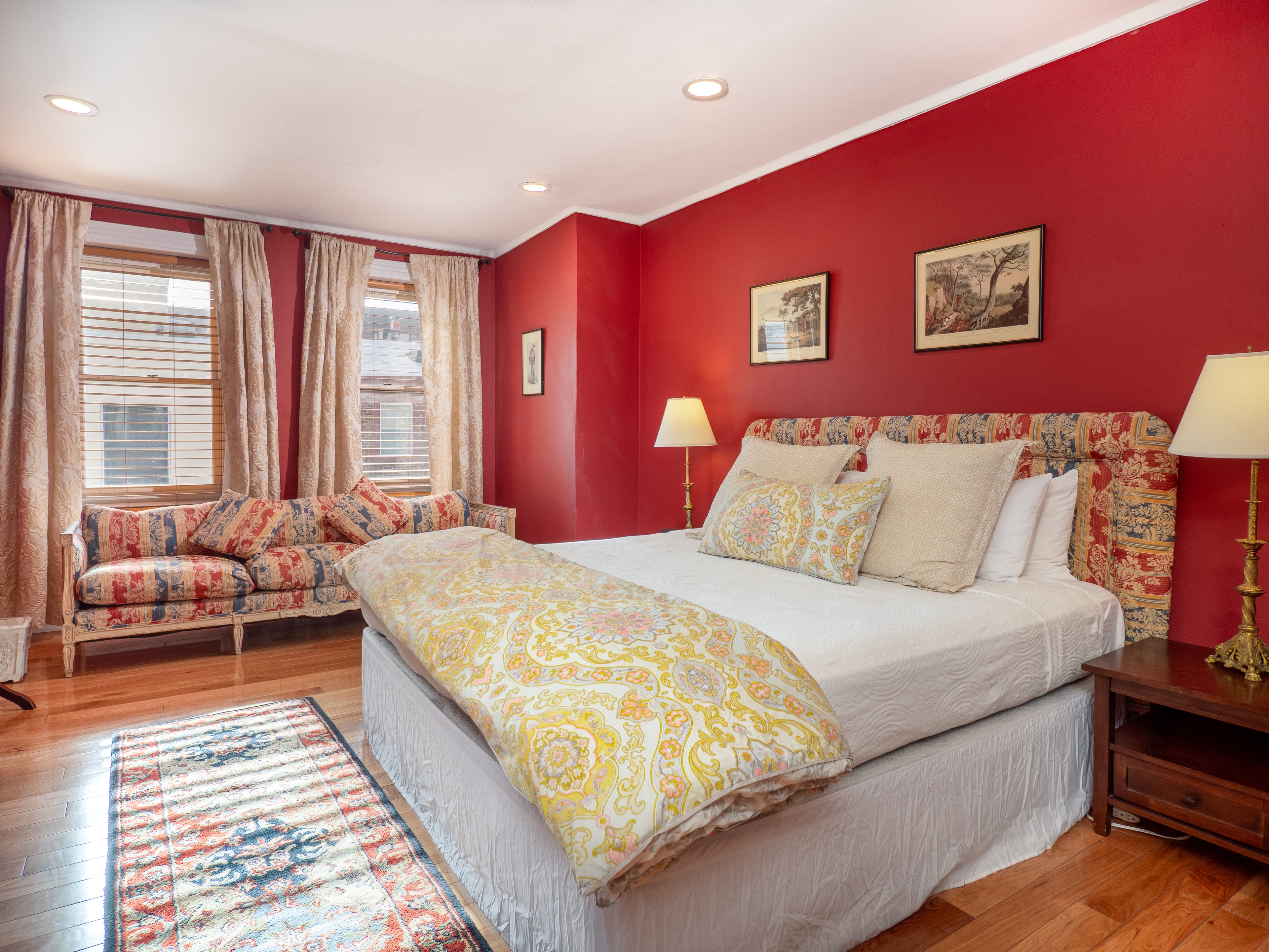 Retro bedroom with queen bed, couch and two bedside tables with antique lamps.