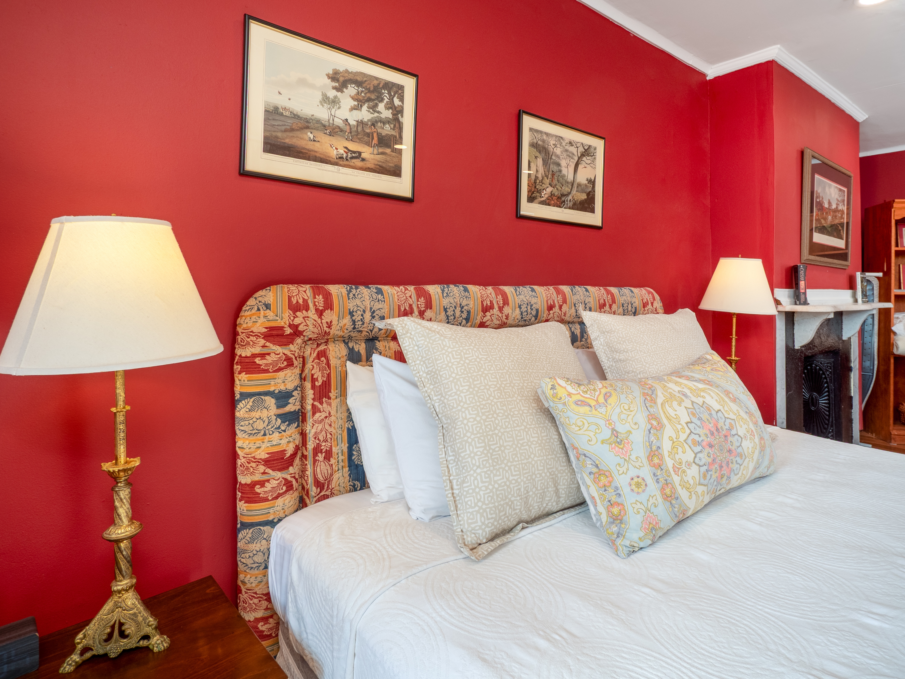 Close up of the bed and two bedside tables with two lamps and photos on the wall.