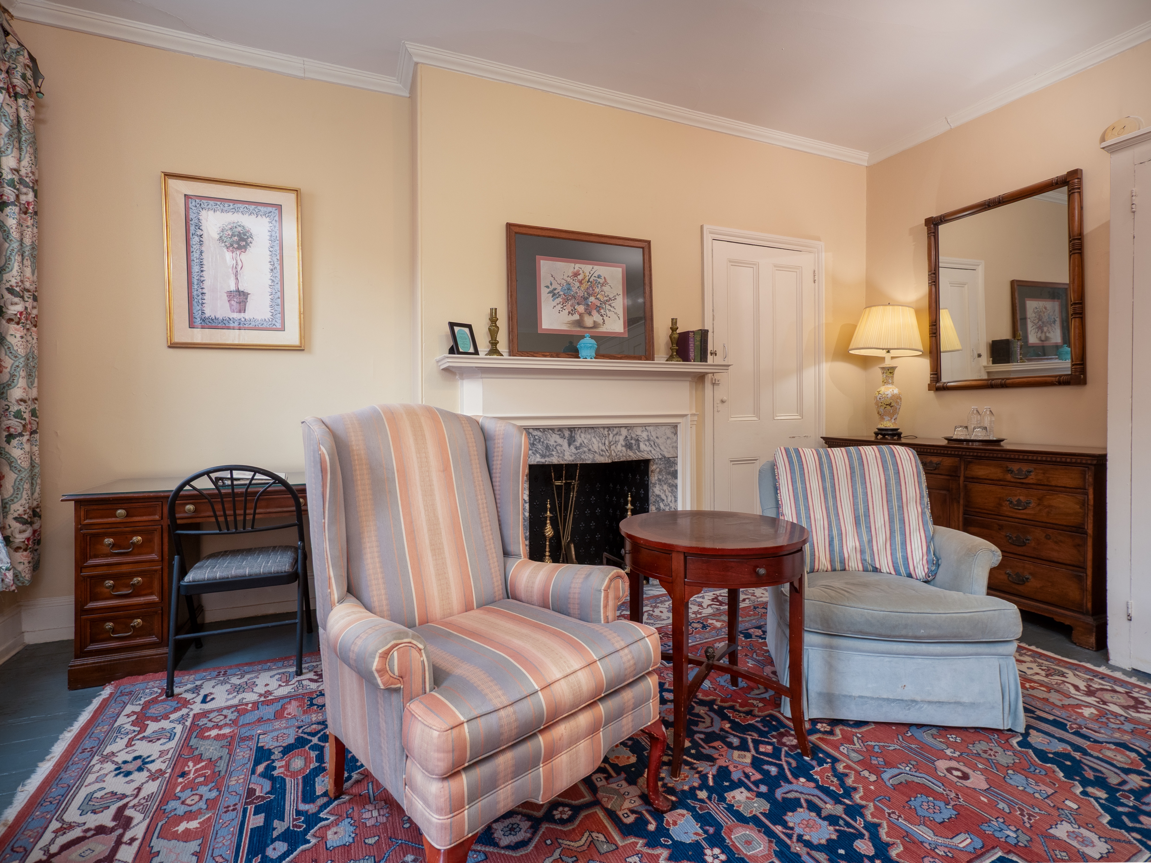 Showcase of matching loveseats with a table between and decorative fireplace behind.