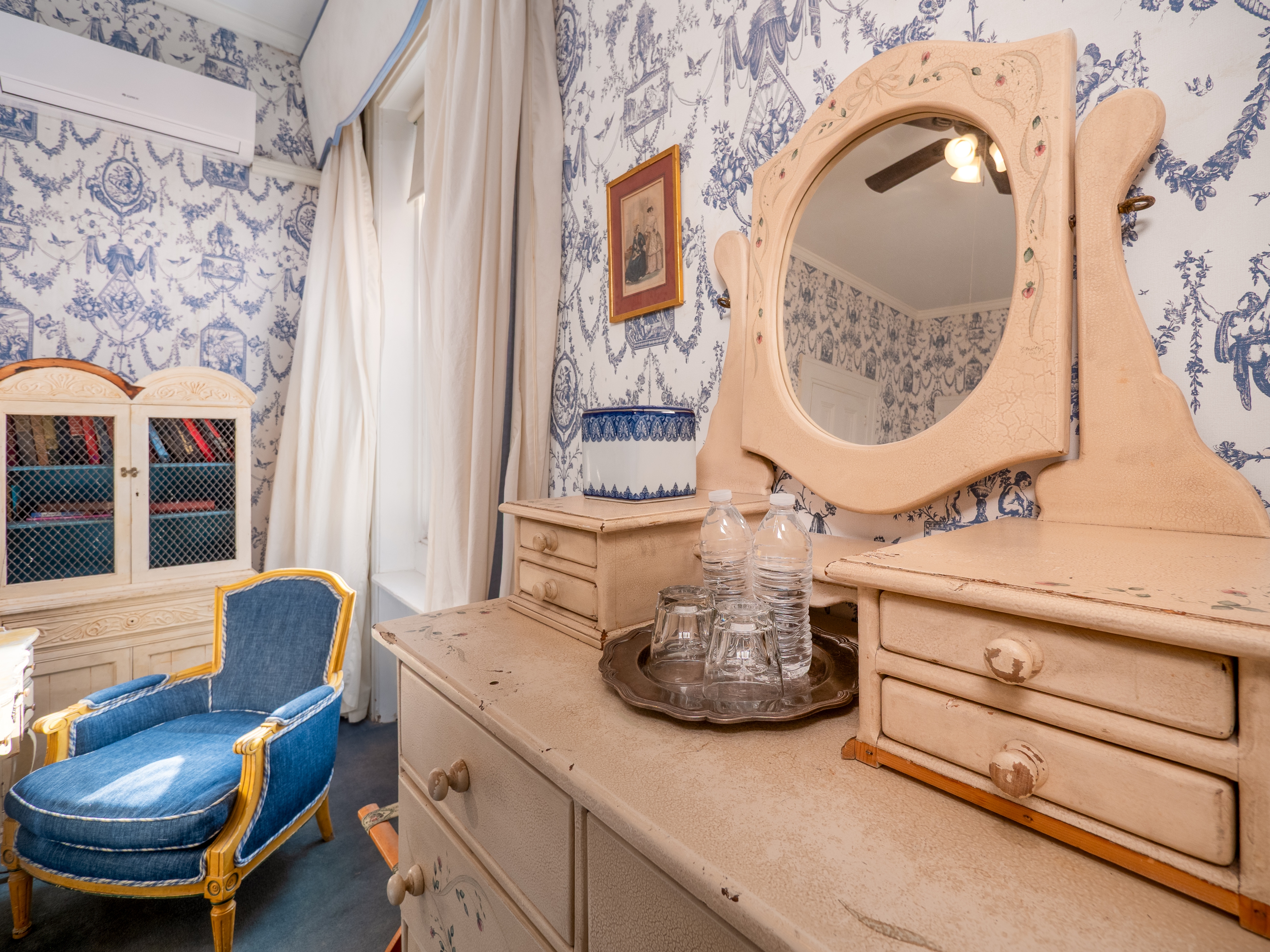 Showcase of the dresser with a mirror and cushioned chair by the window.