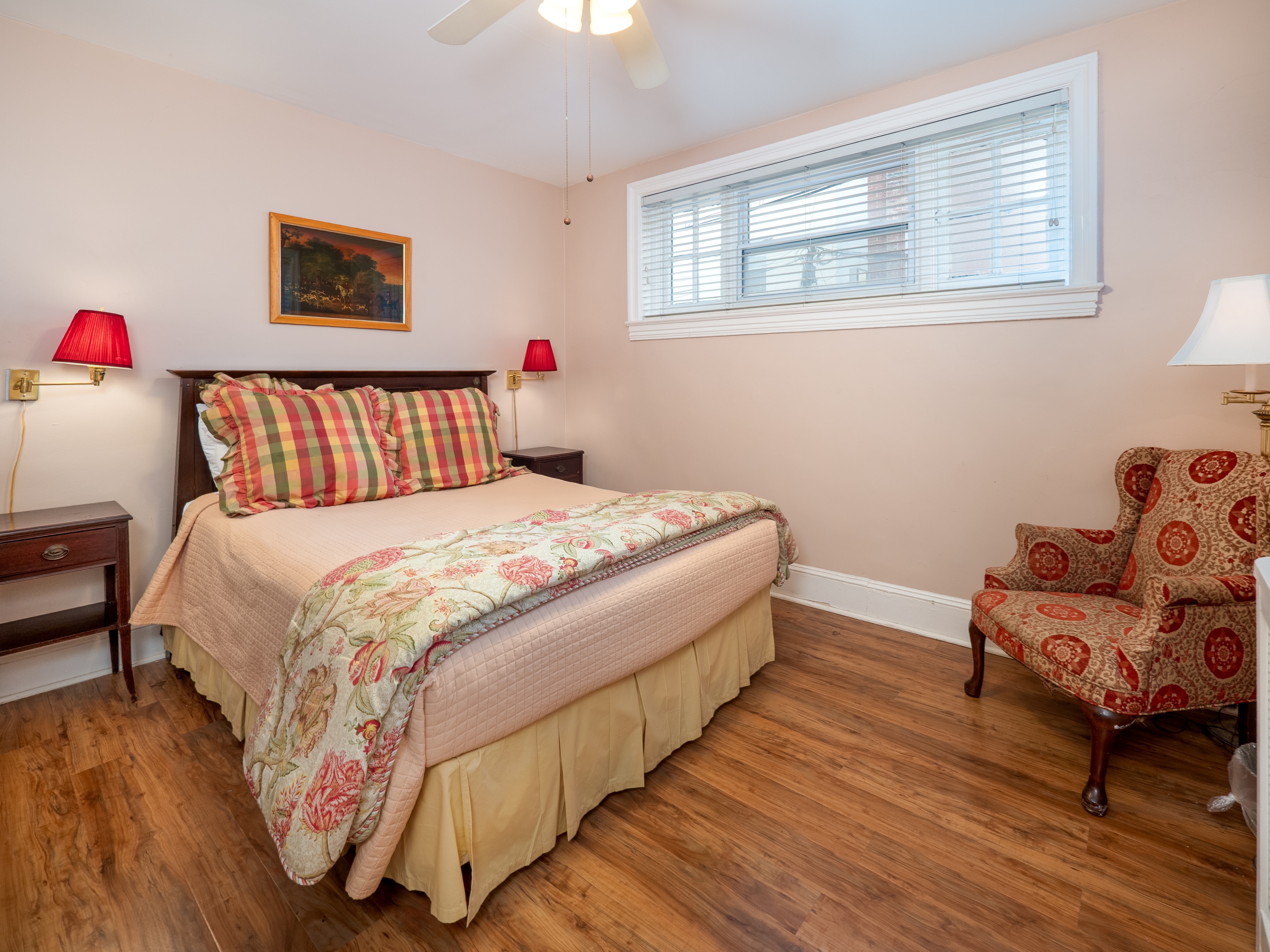 Cozy bedroom with a queen bed that has two side tables and lamps. A window provides natural light.