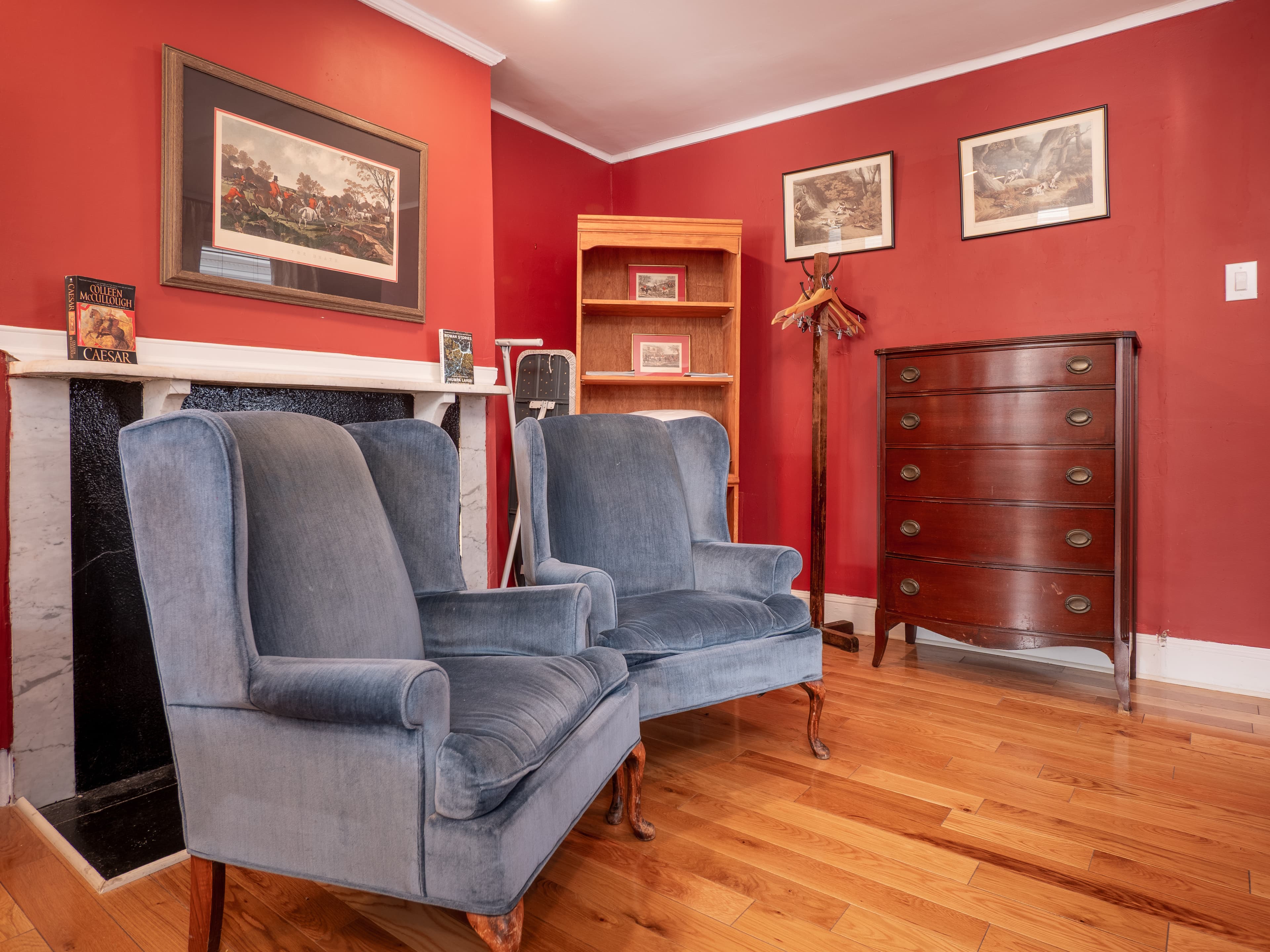 Two matching sofa chairs, a decorative fireplace, dresser and shelf.