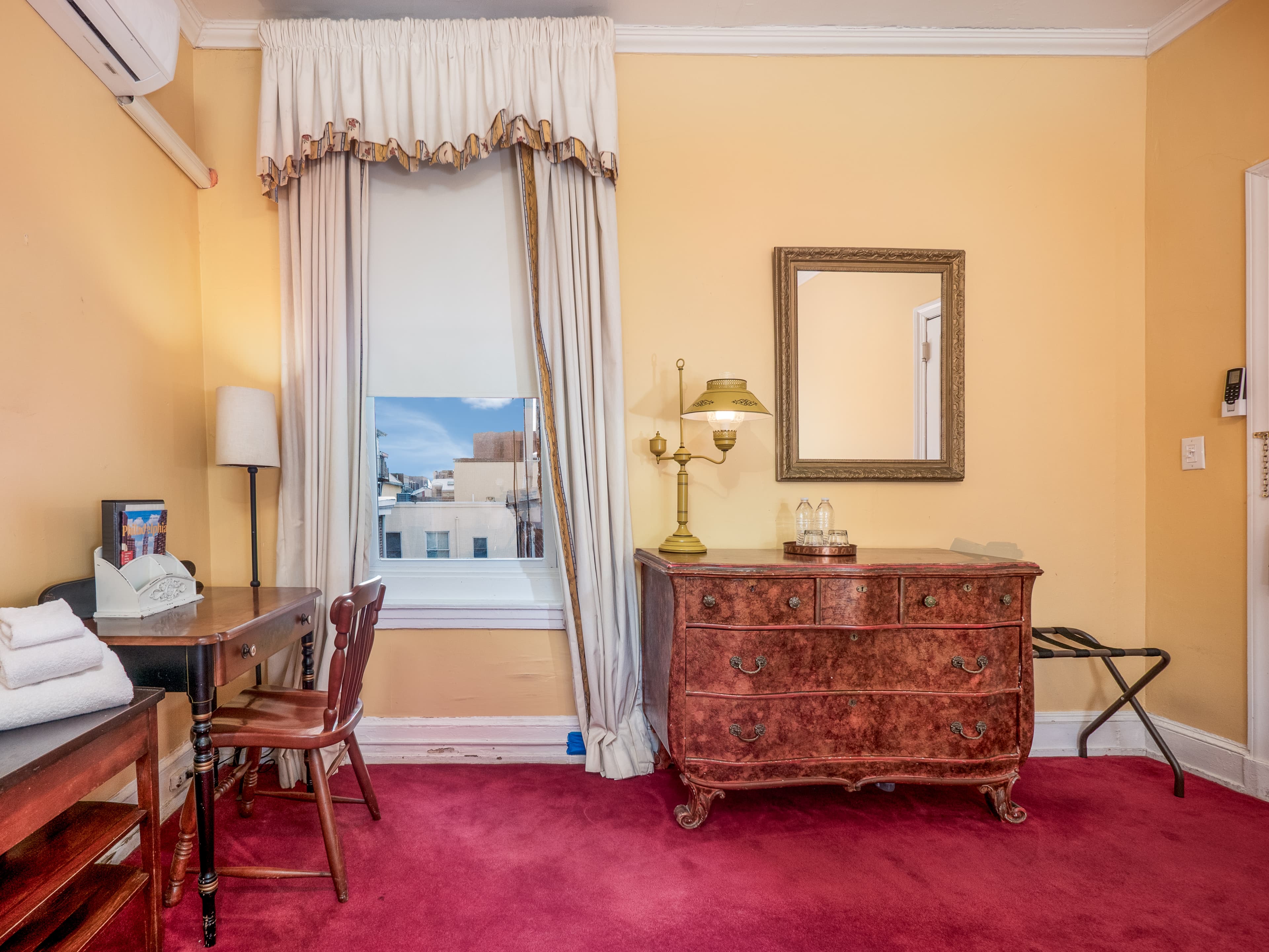 Cozy nook with the window, desk, dresser and wall mirror.