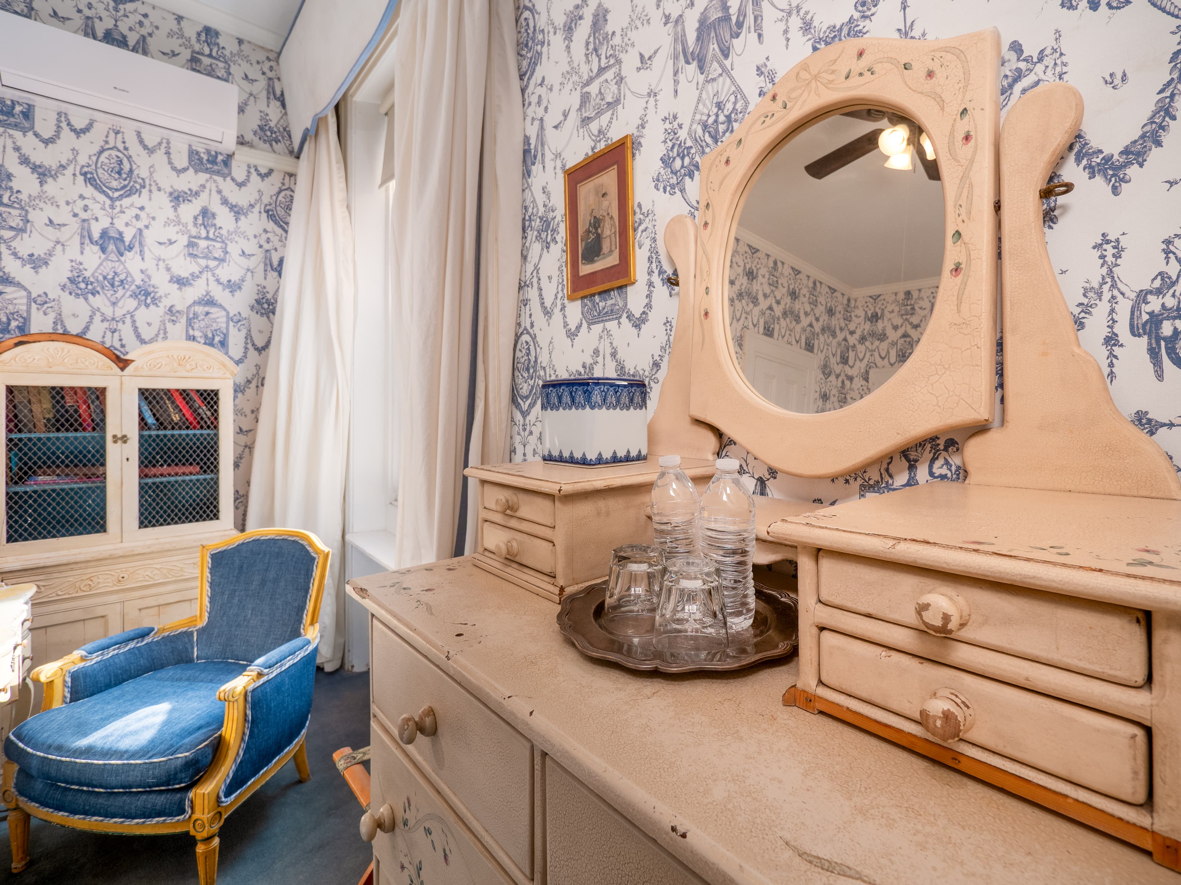 Showcase of the dresser with a mirror and cushioned chair by the window.