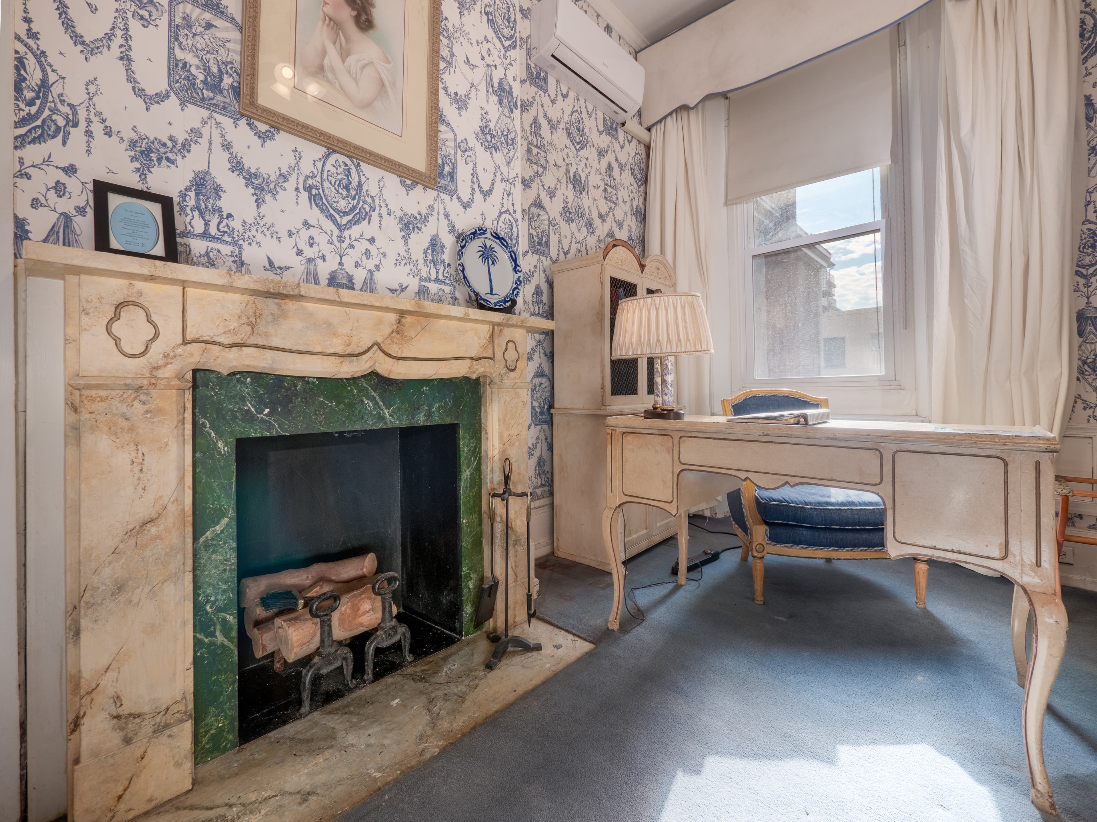Detailed decorative fireplace with a desk, chair and window providing natural light.