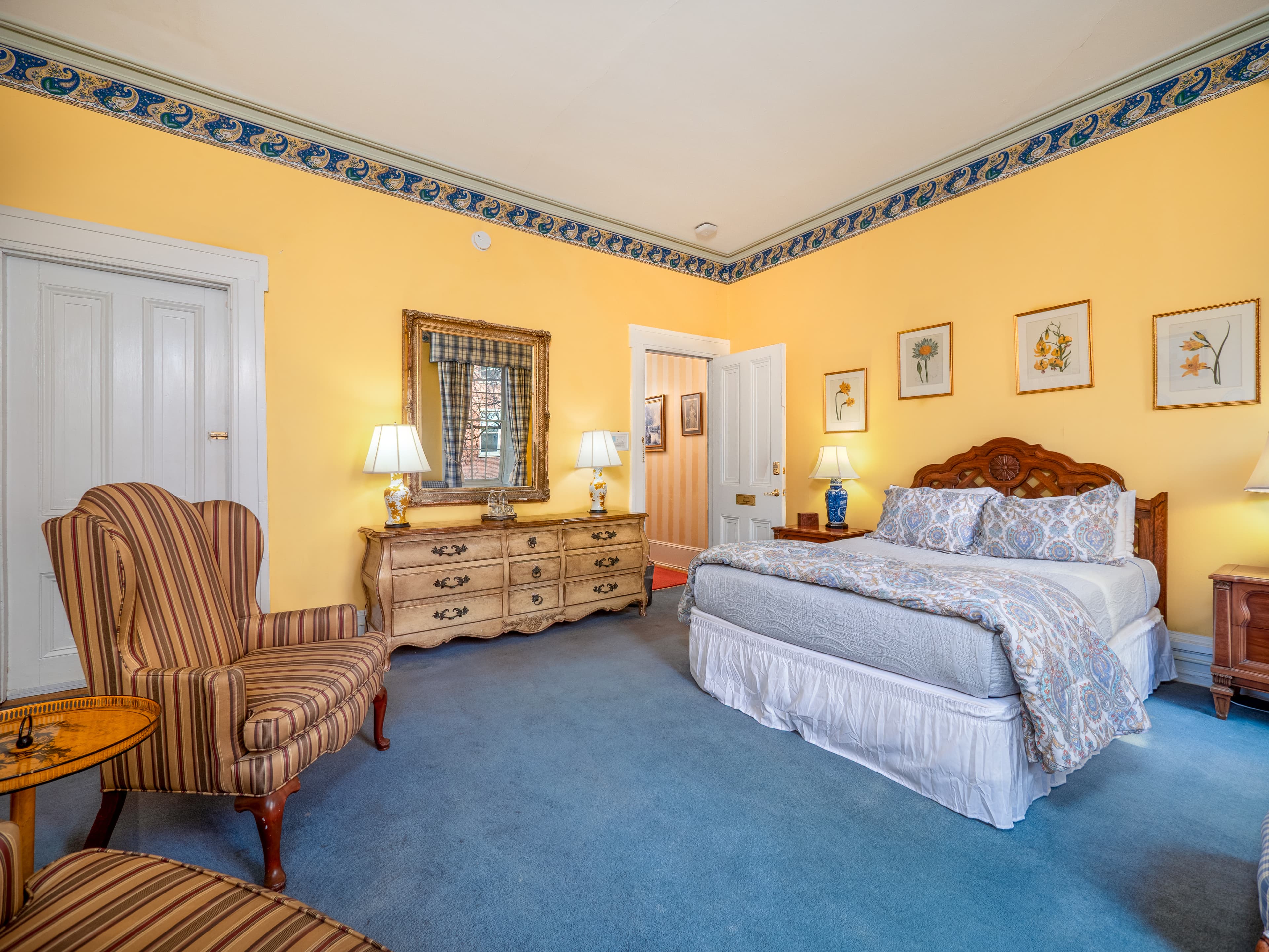 Alternate angle of the bedroom facing the entrance showing the dresser, wall mirror, bed and closet.