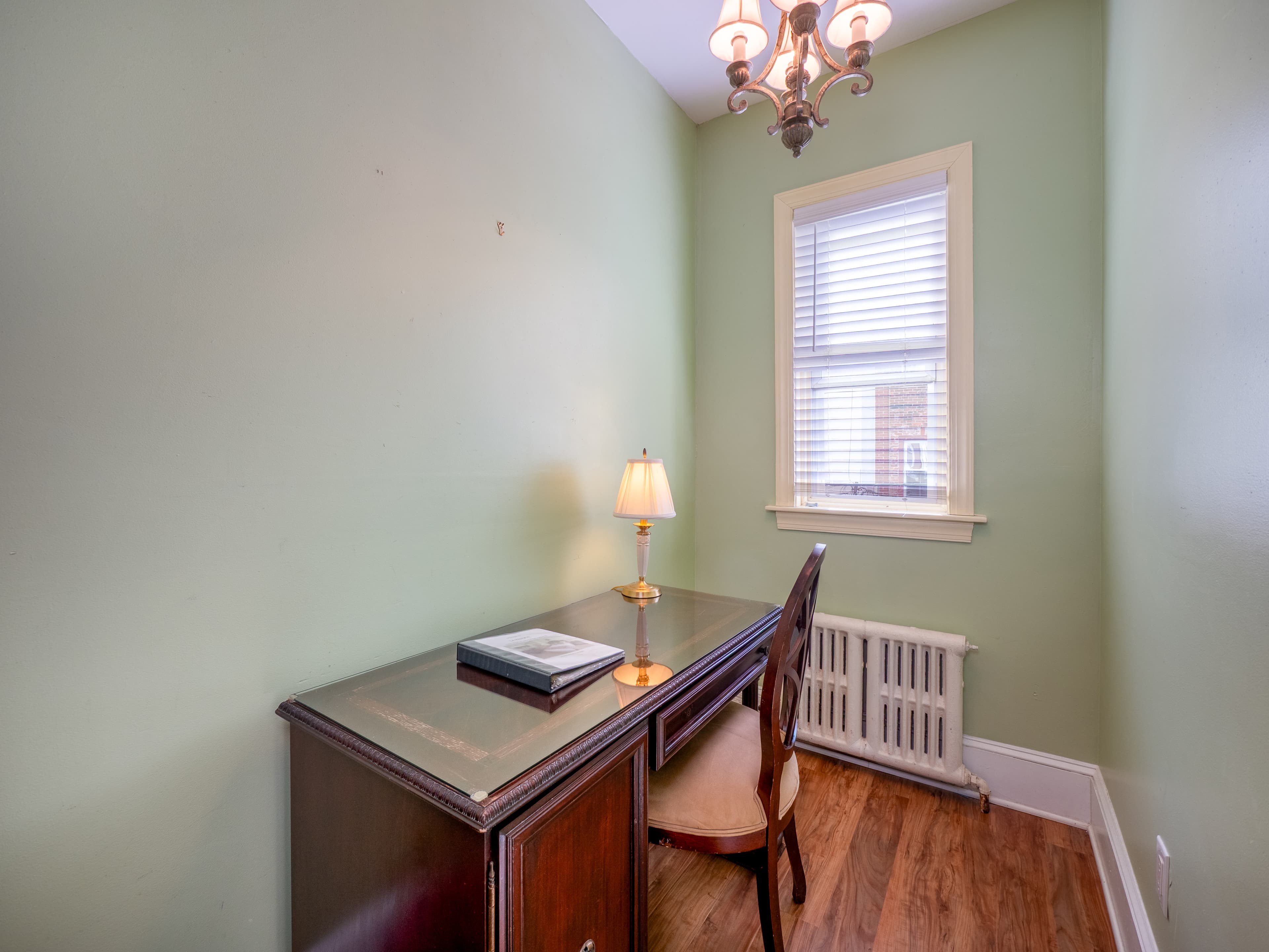 Closeup of the desk area with a window providing natural light and a radiator under the window.