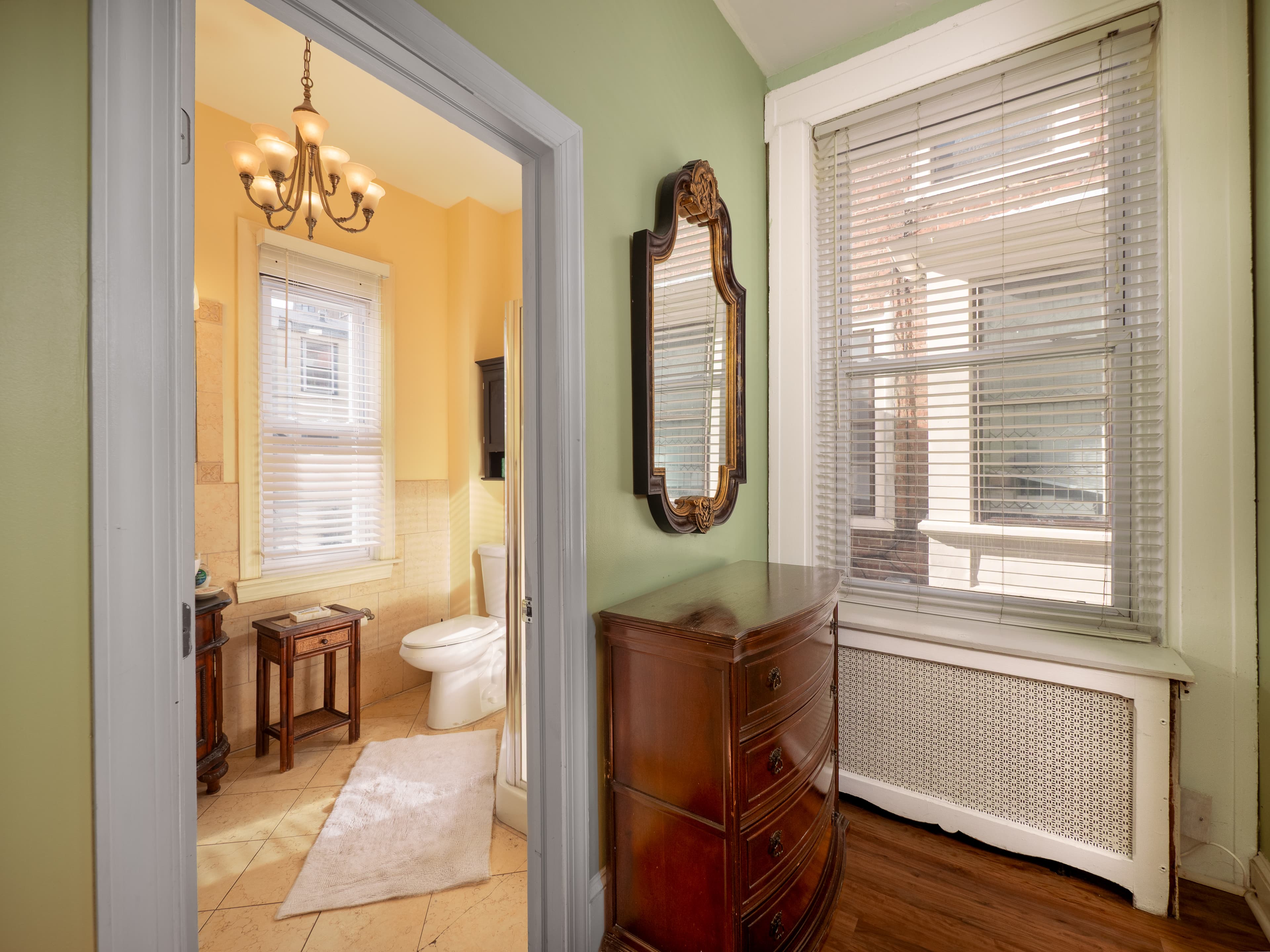 Closeup of the dresser and bathroom entrance. A window next to the dresser provides natural light.