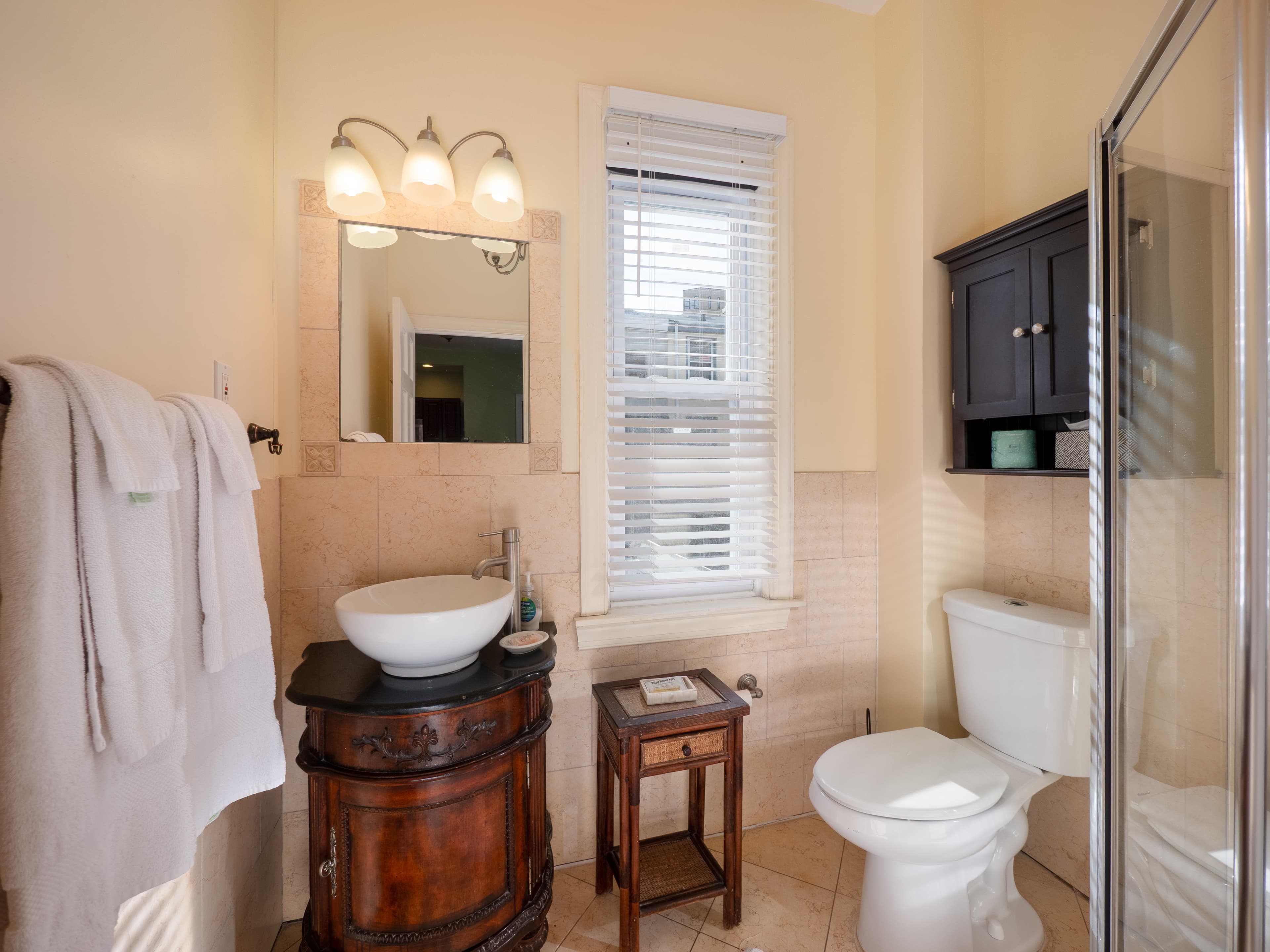 Full bathroom with a cabinet above the toilet and a glass door standing shower.