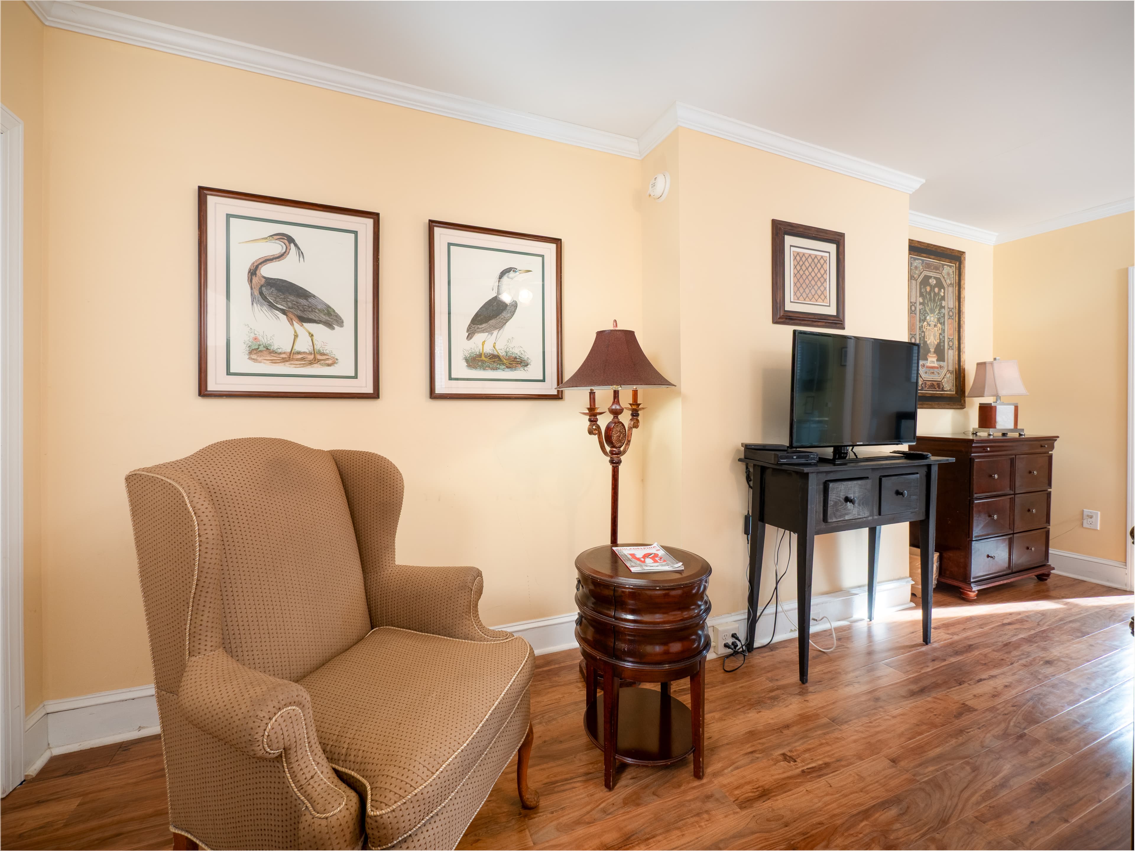 Close up of an armchair with a side table with the TV in the background.