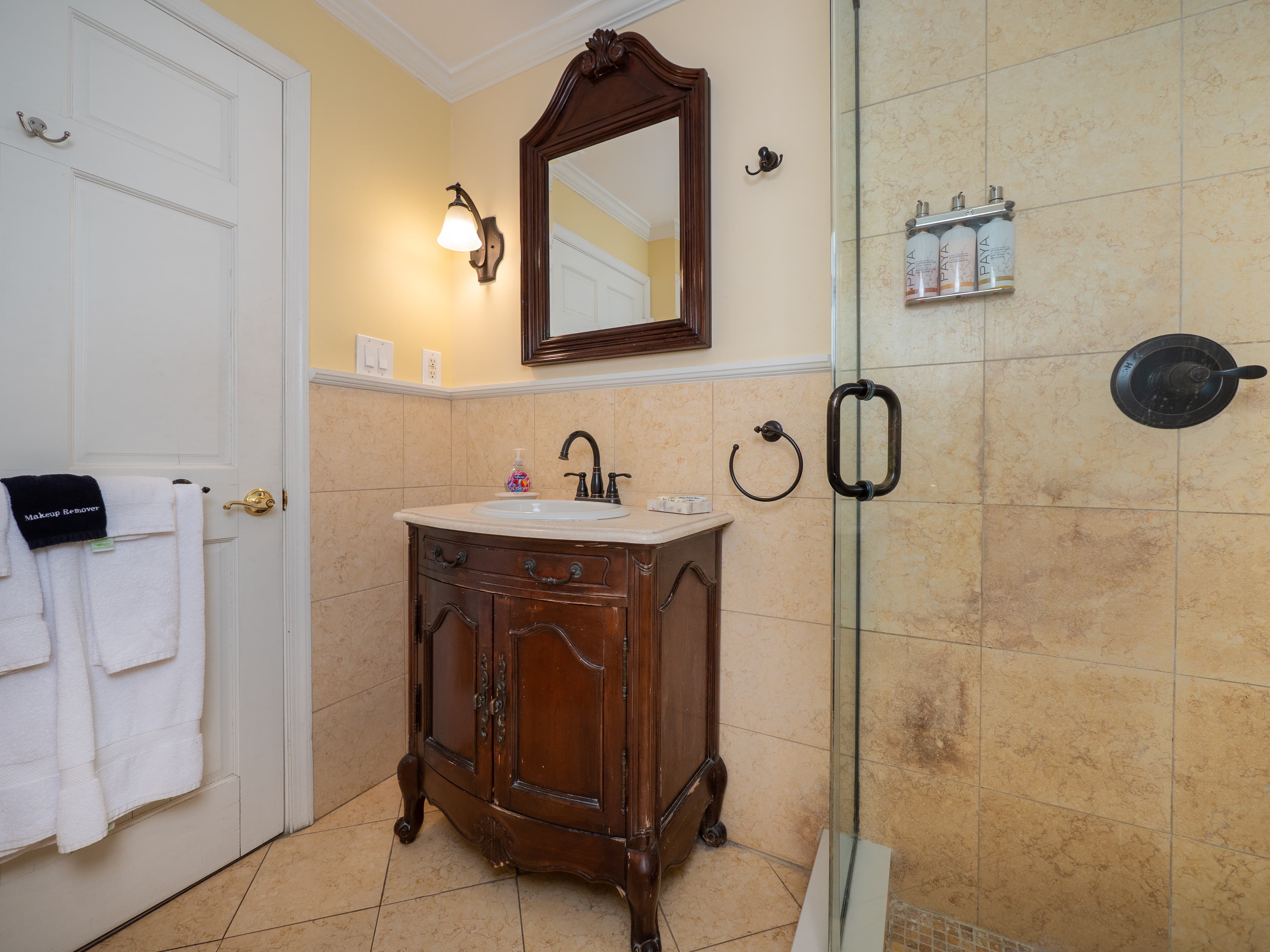 Bathroom sink with a mirror above it. There is a glass door standing shower.