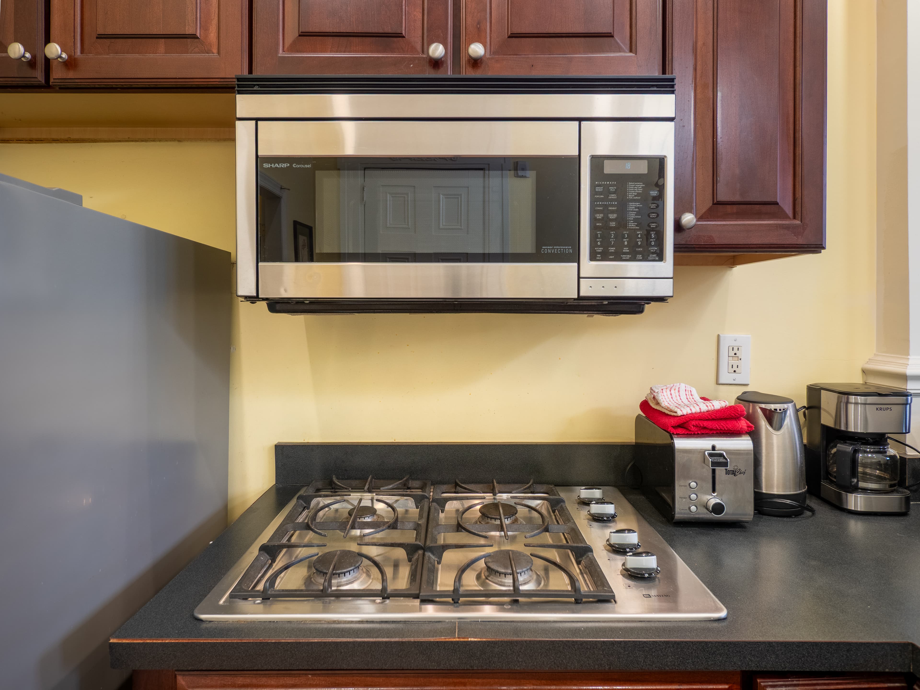 Close up of the stove and microwave above it. A toaster sits next to the stove.