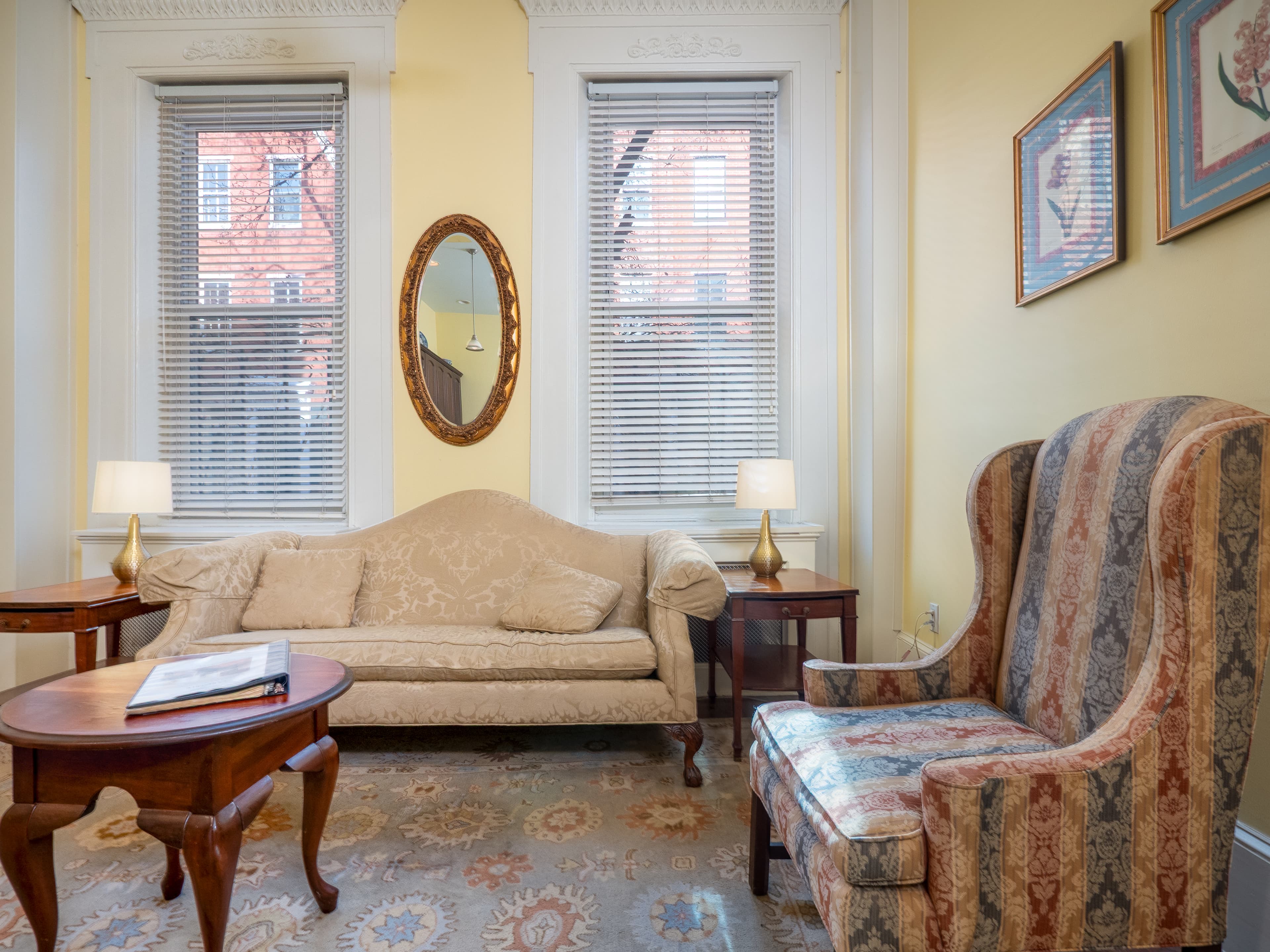 Detail shot of the sitting area with sofa, chairs, small table and windows.