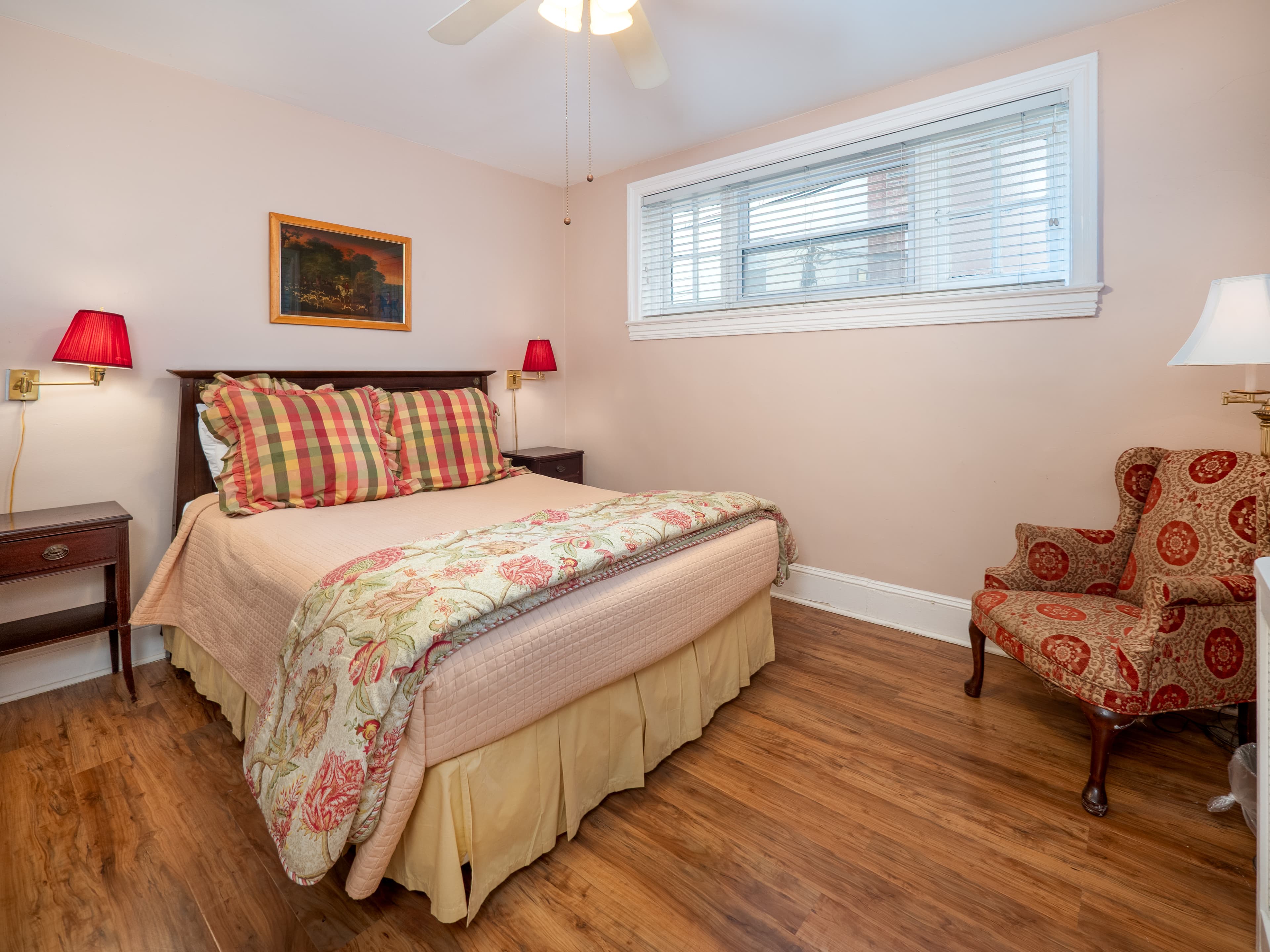 Cozy bedroom with a queen bed that has two side tables and lamps. A window provides natural light.
