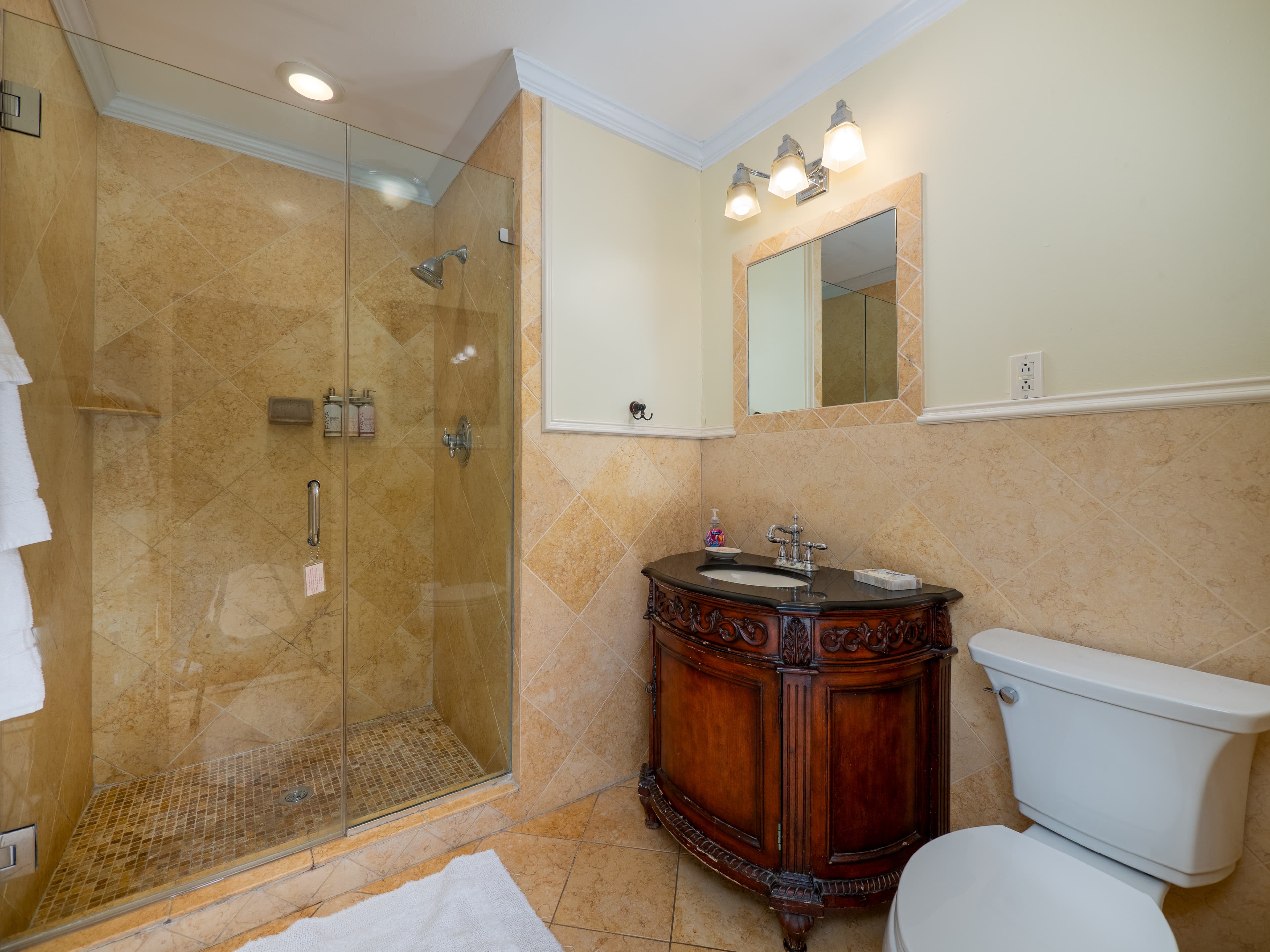 Alternative view of the bathroom showcasing the sink and standing shower with glass door.