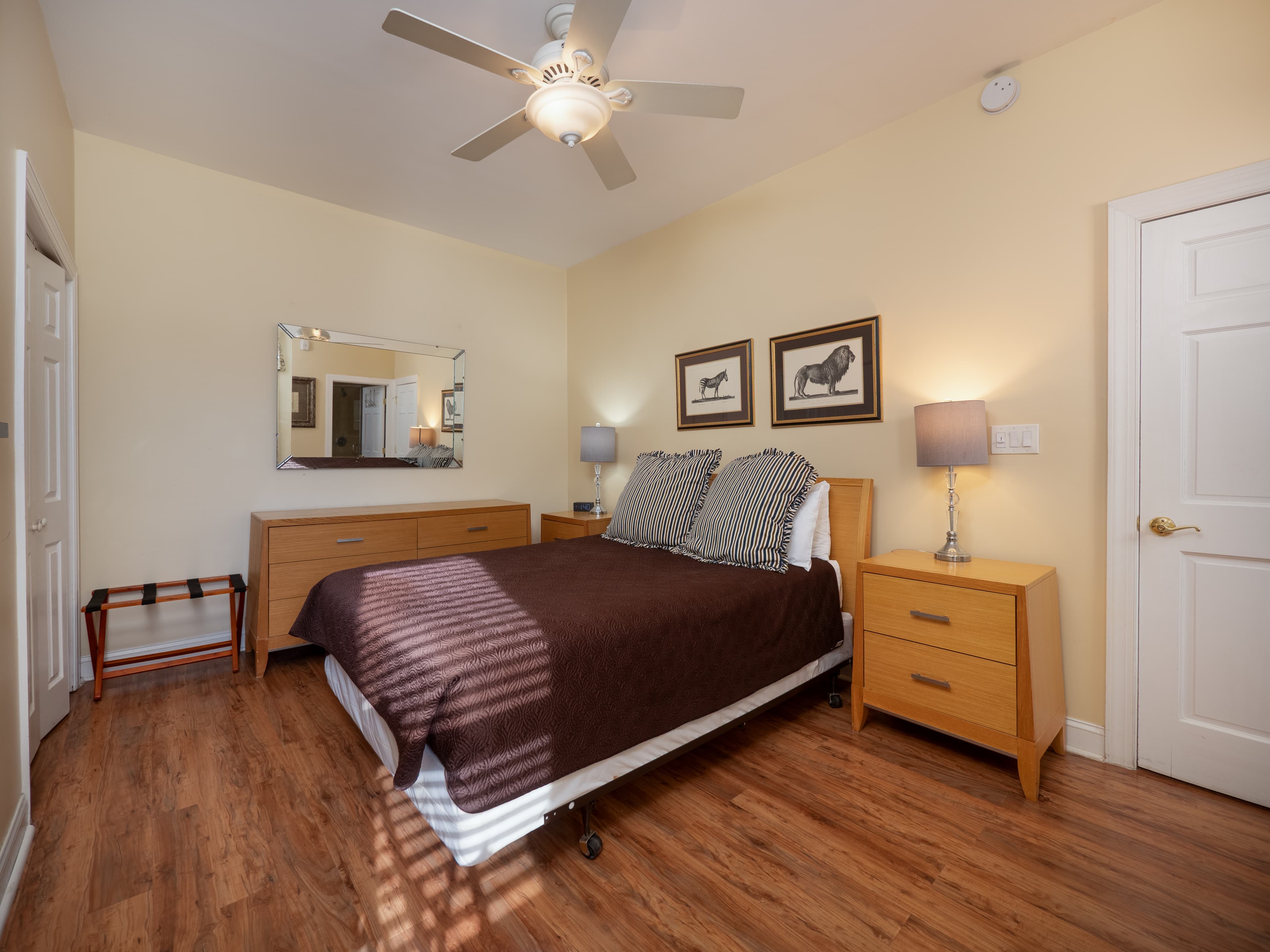 Inviting bedroom with queen bed, ceiling fan, and two side tables with lamps on them.