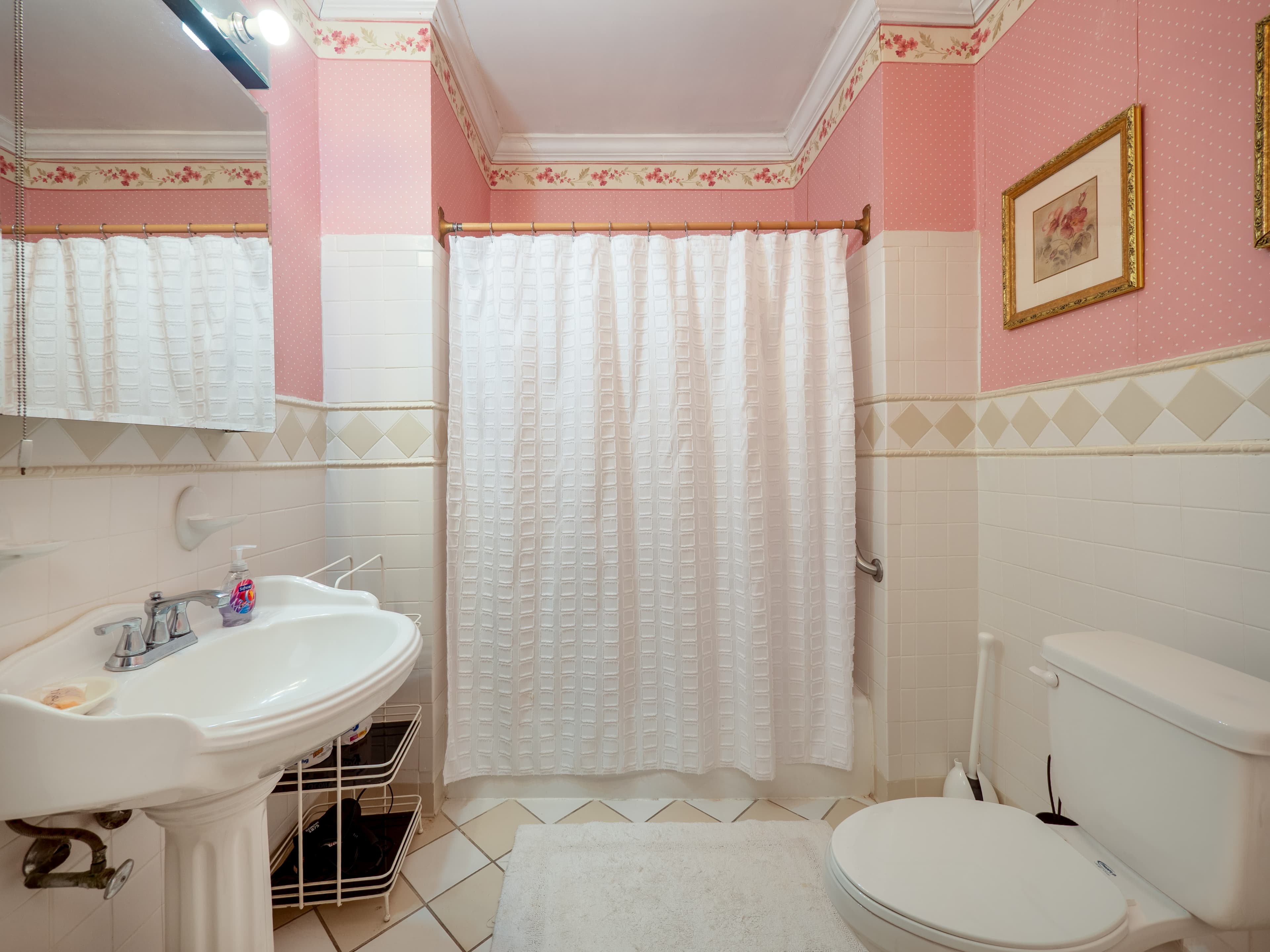 A bright, pastel-colored bathroom featuring a white shower curtain, sink, and toilet.
