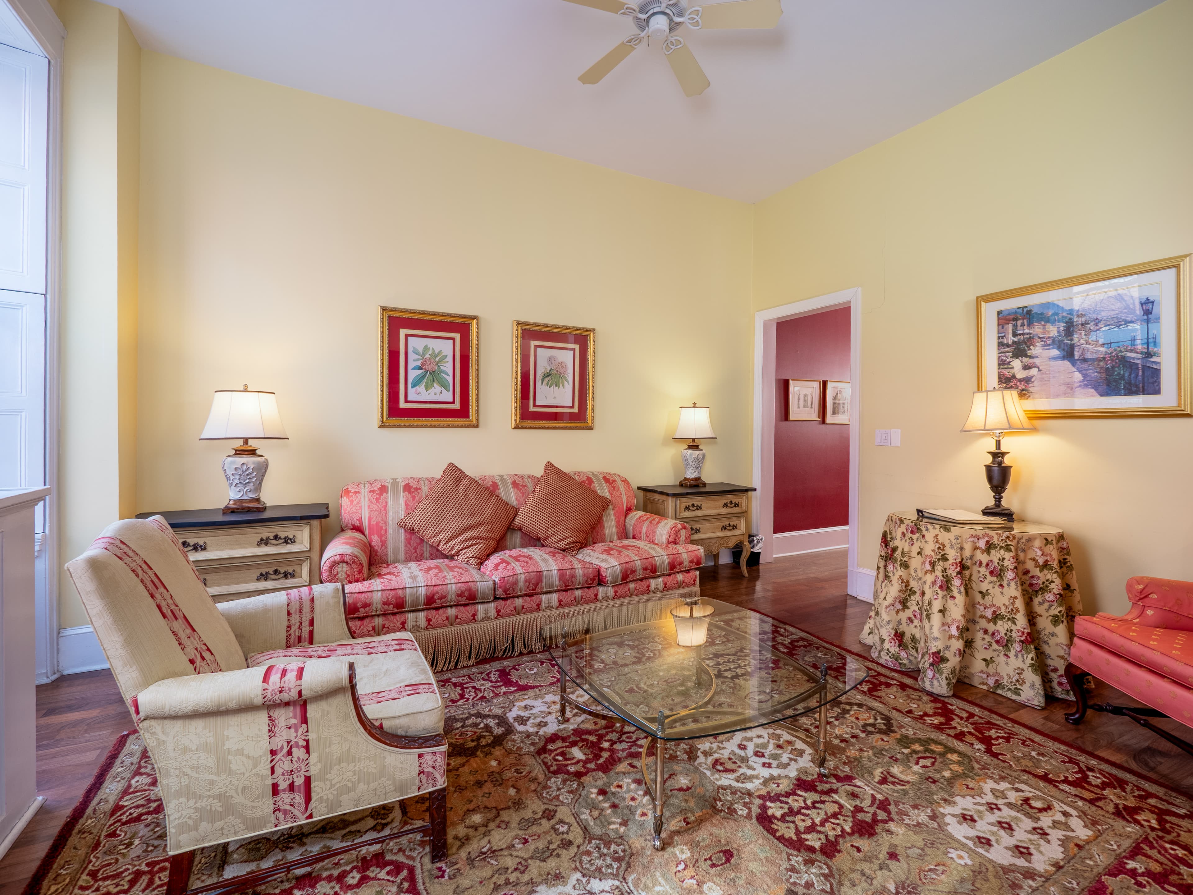 Cozy living room featuring a red-striped sofa, glass coffee table, and warm yellow walls.